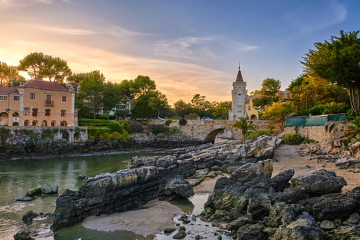 Colorful sunset over Museum of Conde de Castro Guimaraes, Cascais, Portugal. Beautiful building in picturesque location, next to tidal pool, sandy beach, rocky shores and bridge, stylized as Manueline castle.