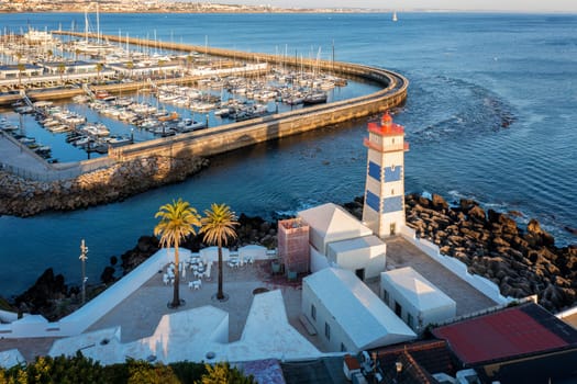 Panoramic view of Santa Marta lighthouse, marina of Cascais, Portugal before sunset on quiet sunny summer evening. Famous landmark by Cascais marina full of sailboats and yachts on Atlantic ocean coast near Lisbon.