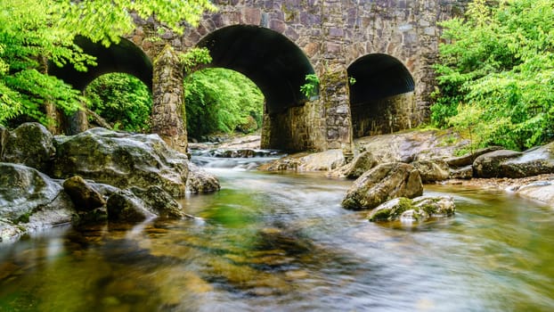 Long exposure image of West Fork Pigeon River under Tripple Arch Bridge near Maggie Valley, North Carolina.