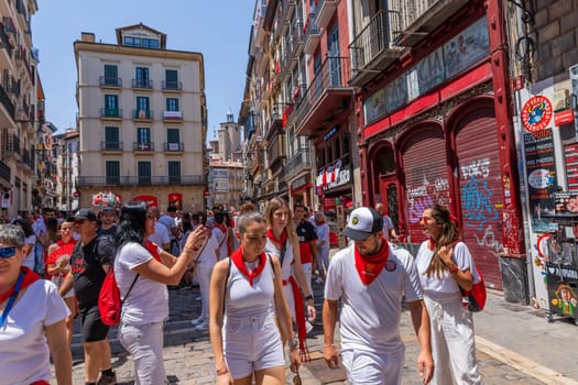 Pamplona, Spain: 09 July 2023: People celebrate San Fermin festival in traditional white abd red clothing with red necktie, Pamplona, Navarra, Spain.