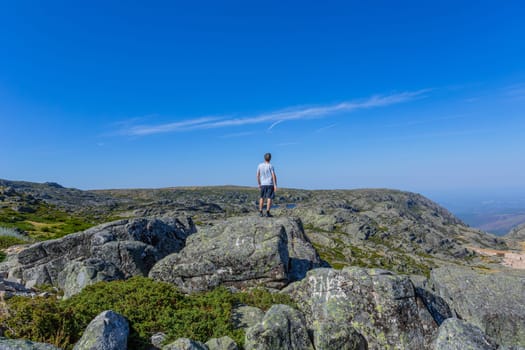Man tourist standing overlooking at picturesque view of the mountain, in Serra da Estrela, Portugal. View from behind