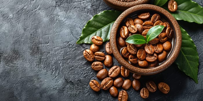 Coffee beans in a bowl and green leaves on a dark background.