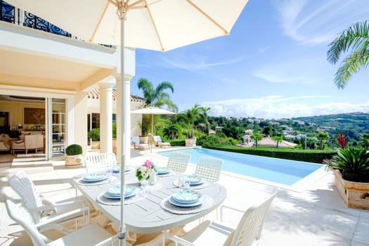An elegant outdoor dining setup by a pool with a view of rolling hills and clear skies.