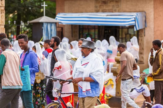 Bahir Dar, Ethiopia - April 21st, 2019: Orthodox Christian people white dressed walk to mass on the street during Easter holiday reflecting the traditions and festive atmosphere of the occasion.
