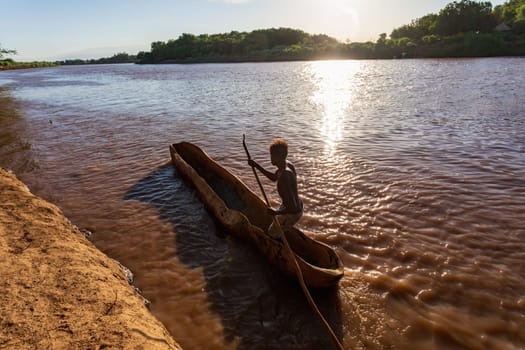 Silhouette of a Ferryman man paddling on a traditional coarse wooden boat, crossing the river Omo, Omo valley, Omorati Etiopia