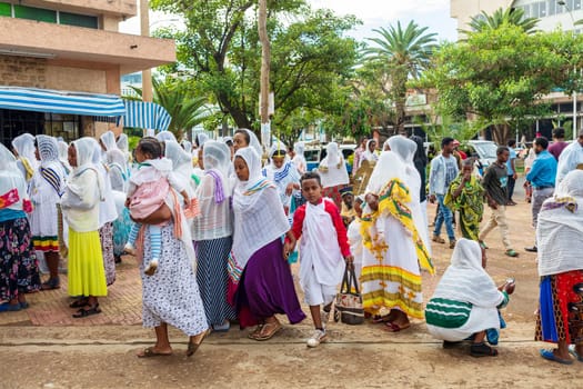 Bahir Dar, Ethiopia - April 21st, 2019: Orthodox Christian people white dressed walk to mass on the street during Easter holiday reflecting the traditions and festive atmosphere of the occasion.