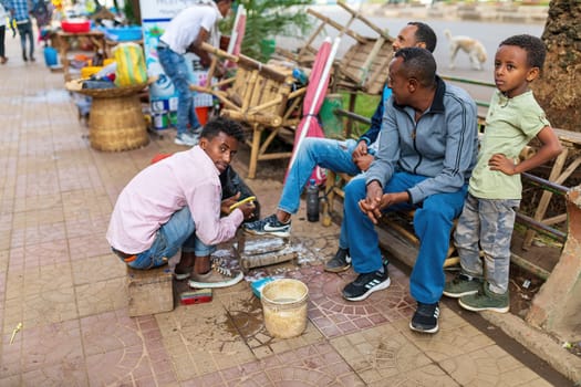 Bahir Dar, Ethiopia - April 21st, 2019: Traditional shoe cleaner on the street of Bahir Dar during Easter holiday.