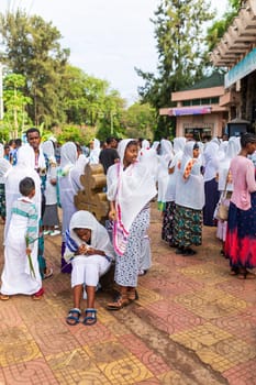 Bahir Dar, Ethiopia - April 21st, 2019: Orthodox Christian people white dressed walk to mass on the street during Easter holiday reflecting the traditions and festive atmosphere of the occasion.