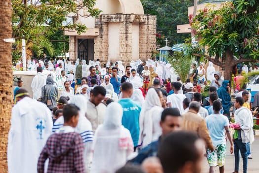 Bahir Dar, Ethiopia - April 21st, 2019: Orthodox Christian people white dressed walk to mass on the street during Easter holiday reflecting the traditions and festive atmosphere of the occasion.