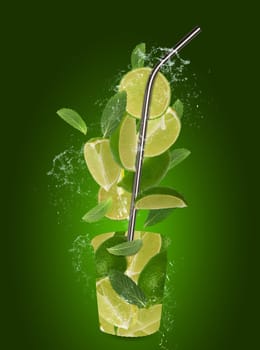 Various lime slices and mint leaves, metal drink straw in splashes of water on a green background, mojito recipe