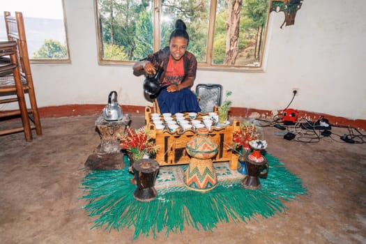 Debre Libanos, Ethiopia - April 27, 2019: Woman perform a traditional Ethiopian coffee ceremony, preparing street bunna coffee.