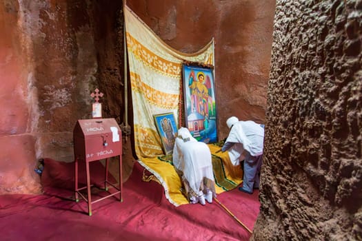Lalibela, Ethiopia - May 1, 2019: A poignant image of worshippers praying inside St. George Church, Lalibela, capturing the spiritual devotion on May 1, 2019.