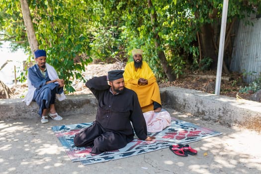 Bahir Dar, Ethiopia - April 21, 2019: Group of Orthodox monk resting in shadows Tana Haik Entons Eysus United Monastery on lake Tana near Bahir Dar. Ethiopia Africa