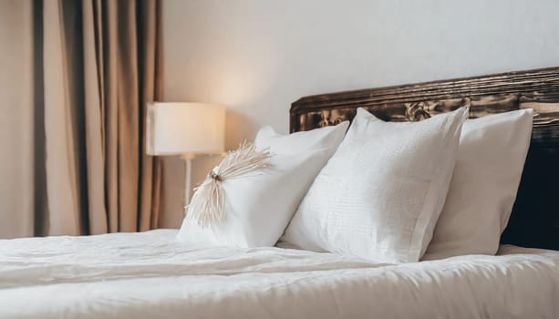 Clean Bedding sheets and pillow on natural wall room background. White bedding and pillow in hotel room. White pillows on empty bed.