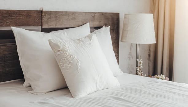Clean Bedding sheets and pillow on natural wall room background. White bedding and pillow in hotel room. White pillows on empty bed.