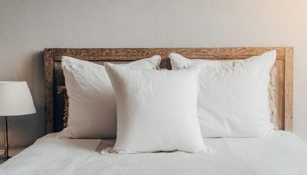 Clean Bedding sheets and pillow on natural wall room background. White bedding and pillow in hotel room. White pillows on empty bed.