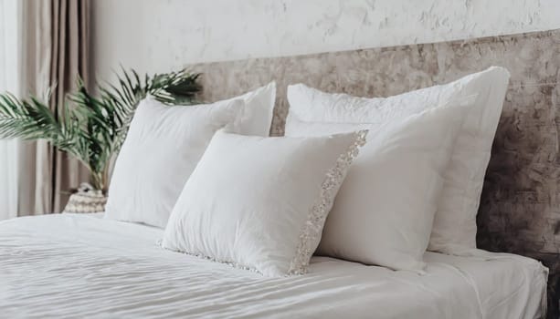 Clean Bedding sheets and pillow on natural wall room background. White bedding and pillow in hotel room. White pillows on empty bed.