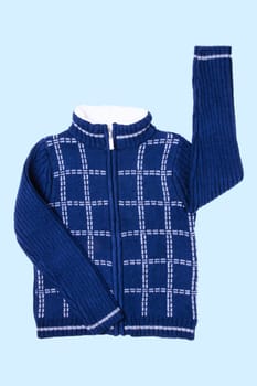 Autumn and winter jacket. A dark blue woolen knitted cardigan or pullover with a white checkered pattern on light blue background. Kids cozy warm jumper or  sweater fashion.
