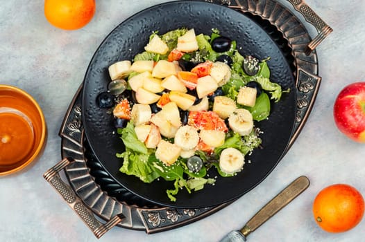 Fruit salad of red orange, apple, banana and lettuce. Healthy eating. Veggie vegan or vegetarian food.