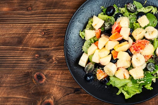 Fruit salad of red orange, apple, banana and lettuce. Healthy eating. Veggie vegan or vegetarian food.