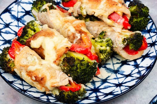 Roast pork meat roll with broccoli and bell pepper. Hot appetizing meal.