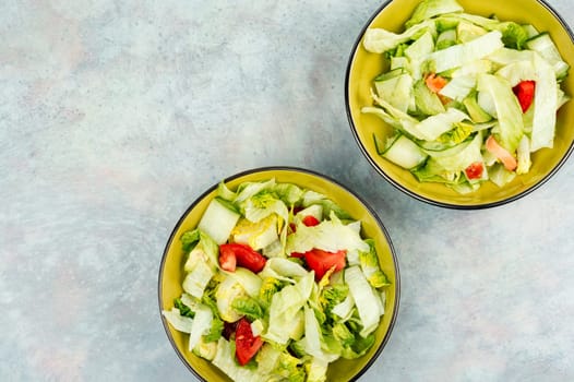 Healthy salad bowl with different lettuce, avocado, cucumber and tomato.