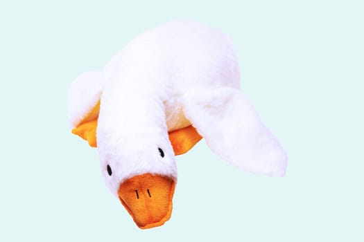Childrens toy stuffed animals. Soft white plush toy duck for kids isolated on a light blue background. Duck teddy toy. White duck for playing.