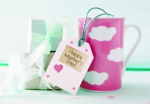 Mothers day greeting card. Decorative composition of gift boxes and coffee mug with tag with Happy mother’s day text. Card with holiday design.