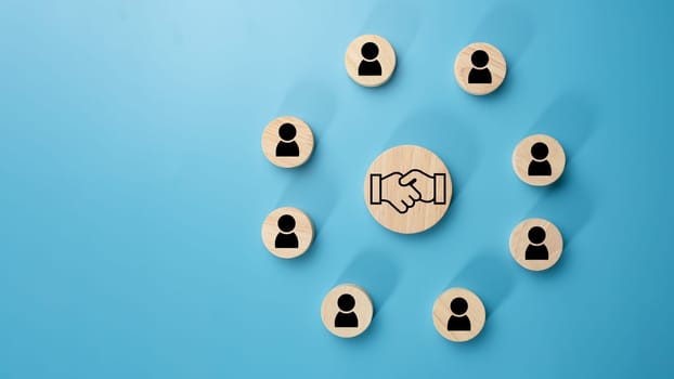 Team management concept, Human resources, Recruitment concept, HRM administration or human resource management concept, The handshake icon in a circular wooden board placed on a light blue background.