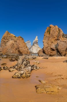 Towering rock cliffs at Praia Da Ursa Beach, Sintra, Portugal. Atlantic ocean waves and sandy beach near famous Cabo da Roca in Portugal