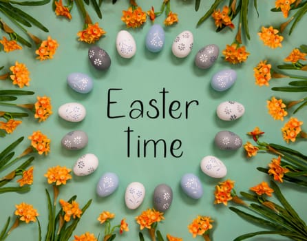Flat Lay With English Text Easter Time. Easter Egg Decoration With Orange Spring Flowers. Light Green Paper Background.