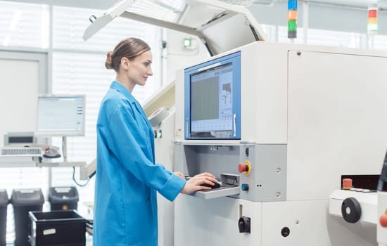 Woman worker at visual inspection of PCB on electronics assembly line looking at screen