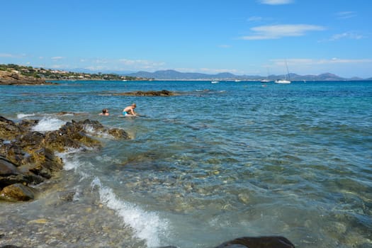 Two children play in the water on a rocky coast on the Côte d’Azur in France