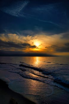 Sunset, illuminated sea. Sandy beach in the foreground. Light waves. Baltic Sea. Landscape on the coast