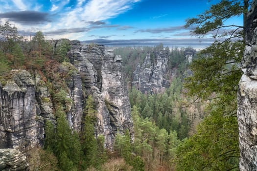 Rugged rocks on the Basteibridge. Wide view over trees and mountains. National park in Germany