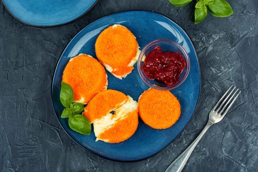 Fried camembert or brie cheese with berry jam and basil. Cheese baked in the oven.