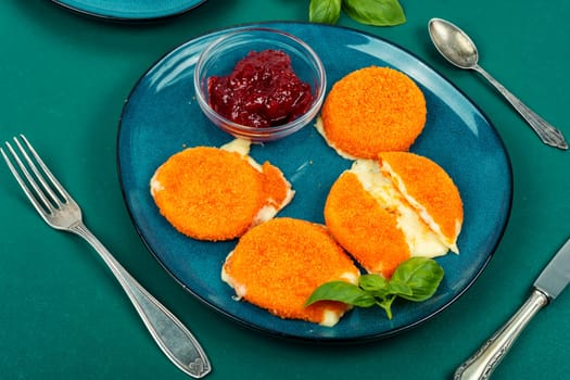Fried camembert or brie cheese with berry jam and basil. Cheese baked in the oven.
