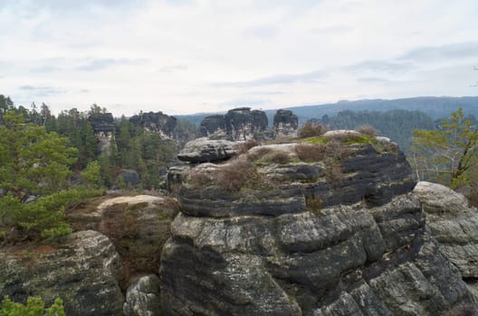 Rugged rocks on the Basteibridge. Wide view over trees and mountains. National park in Germany
