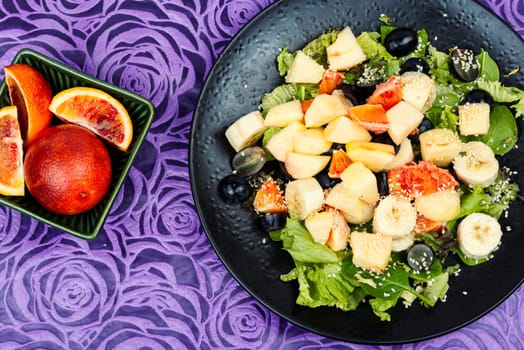 Raw fruit salad of red orange, apple, banana and herbs.