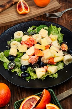 Raw fruit salad of red orange, apple, banana and herbs.