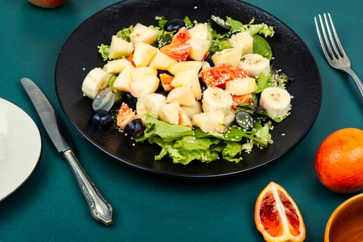 Raw fruit salad of red orange, apple, banana and herbs.