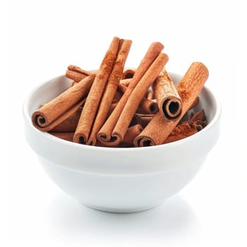 A collection of cinnamon sticks rest in a ceramic bowl on a white background. The cinnamon sticks are a warm brown color and some are rolled together