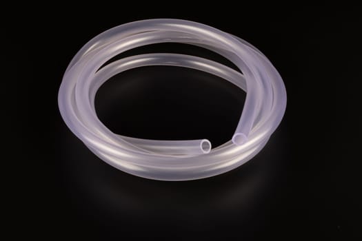 transparent plastic tube coil on black background.