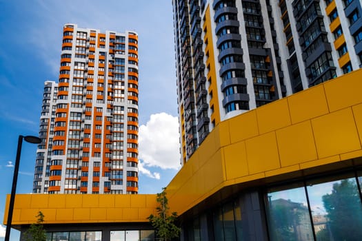 freshly built high rise apartment buildings on blue sky background with white clouds, low angle view