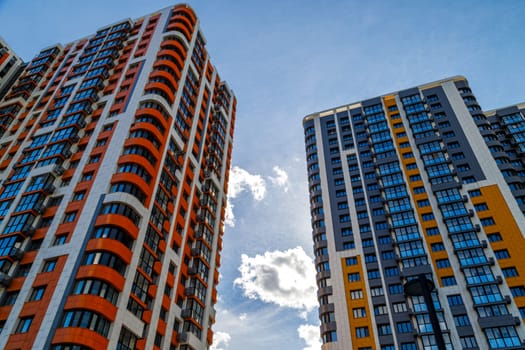 freshly built high rise apartment buildings on blue sky background with white clouds, low angle view