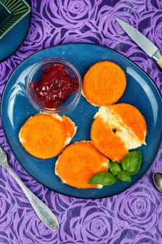 Homemade baked or fried camembert cheese with berry sauce on rustic wooden surface.