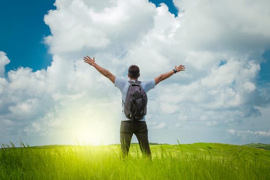 backpacker man in the field spreading his hands, concept of successful man spreading his hands