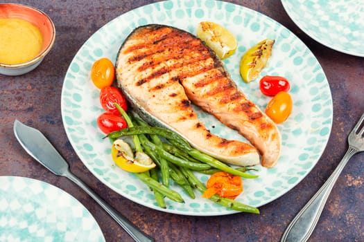 Grilled salmon steak with grilled vegetables, fried fish. Space for text.