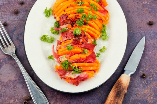 Plate with roasted pumpkin with bacon. Baked butternut squash with bacon. Copy space.