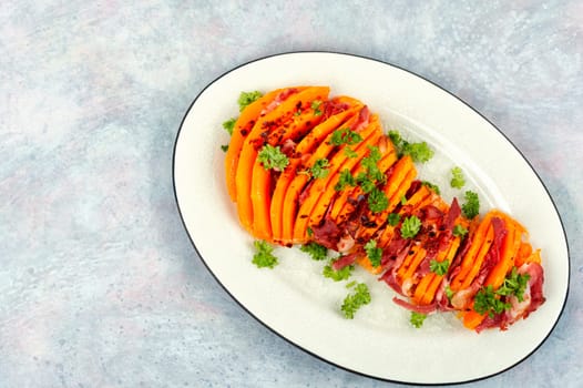 Plate with roasted pumpkin with bacon. Baked butternut squash with bacon. Copy space.
